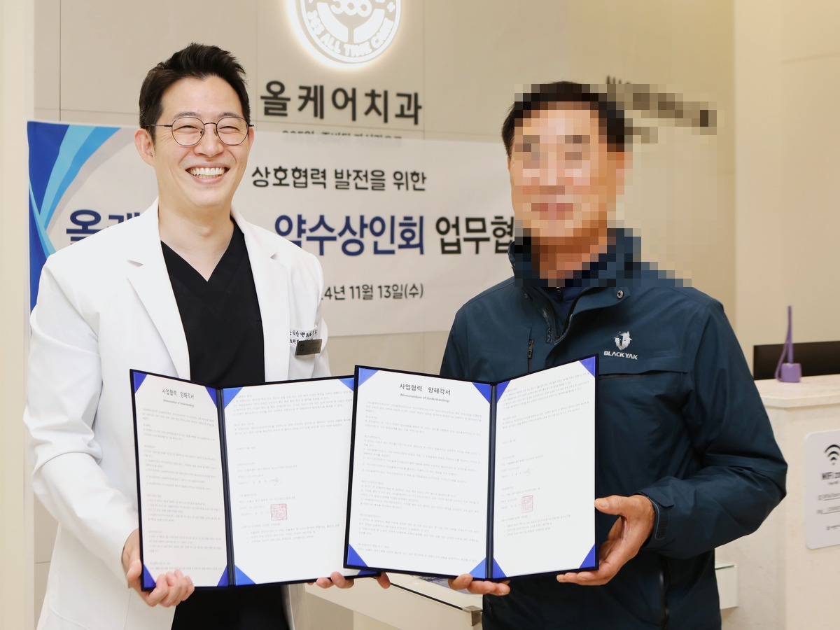 365올케어치과 - 약수시장상인회 업무협약식, 권민수 대표원장이 상인회 측과 상호협력 협약서를 든 모습(상대측 얼굴 모자이크 처리)